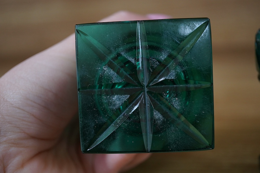 A pair of Regency dark green glass fan cut salts, on square plinths, 9cm. Condition - good, one small chip